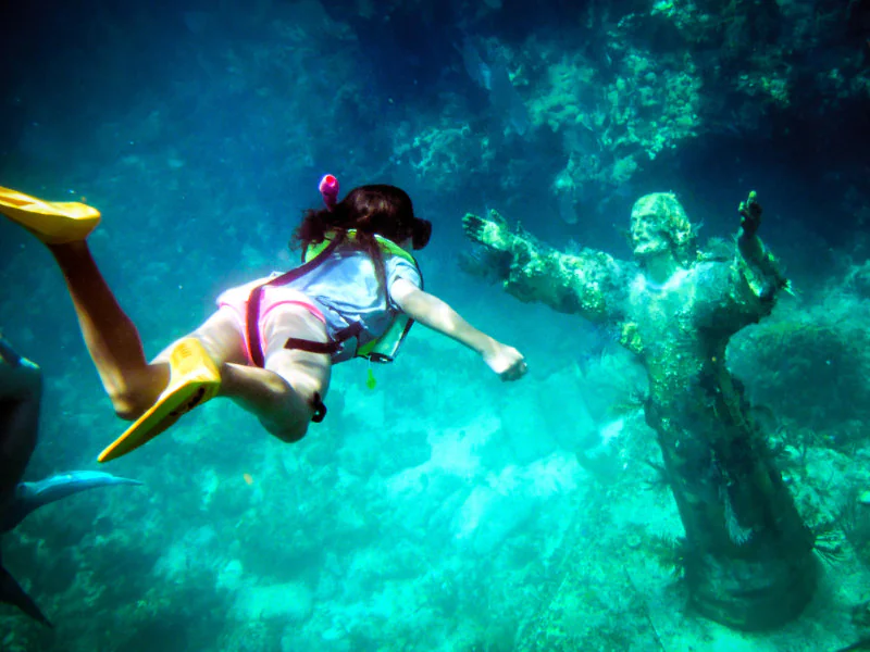 A snorkeling woman and a statue